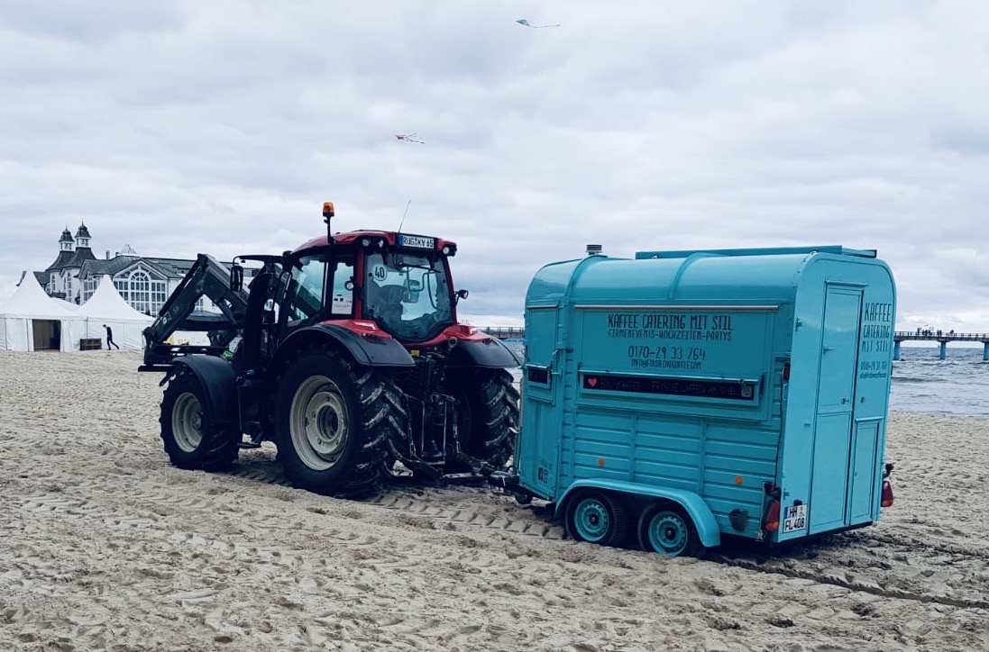 FirstLoveCoffee Kaffeeanhänger wird mit dem Traktor am Strand transportiert
